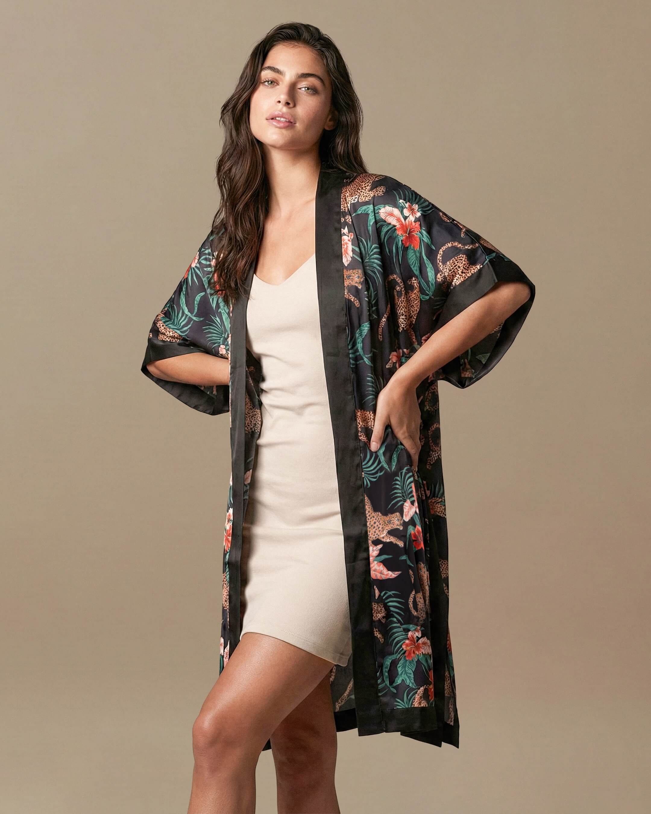 Woman wearing a black floral kimono over a white dress against a beige background